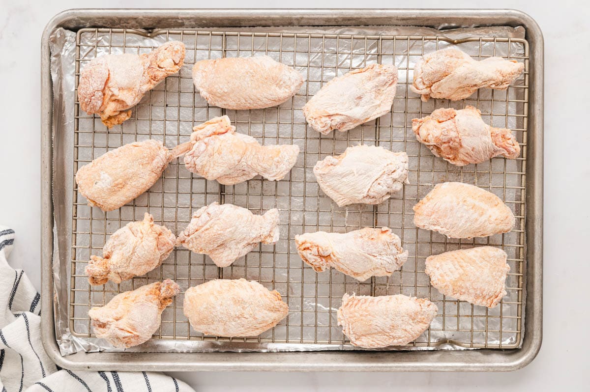 flour coated chicken wings on a wire rack over a baking sheet.