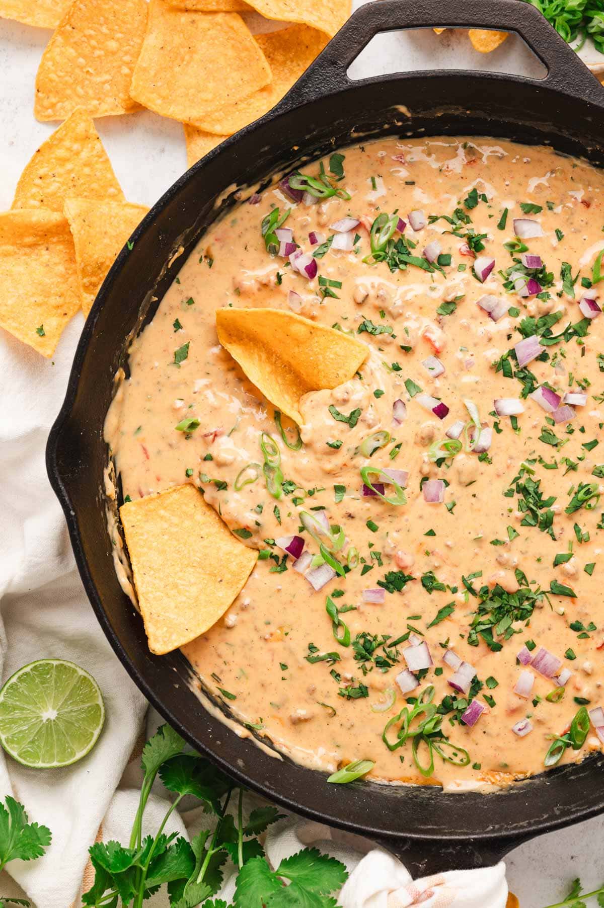 Chili con queso in a cast iron skillet with tortilla chips.