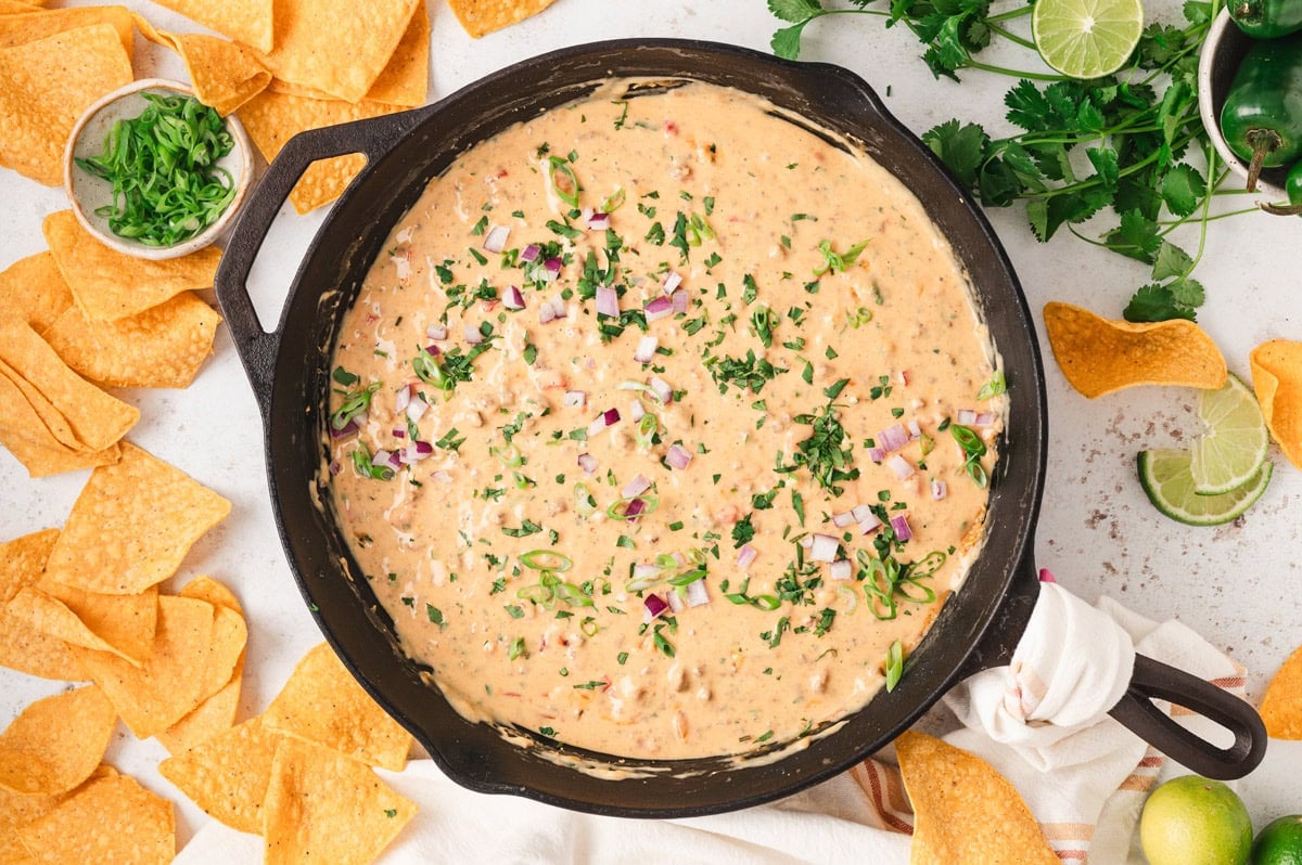 Chili con quesa in a skillet surrounded by tortilla chips.