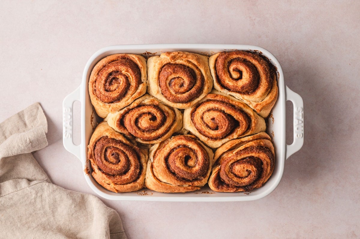 Baked cinnamon rolls in a white baking dish (no icing). 