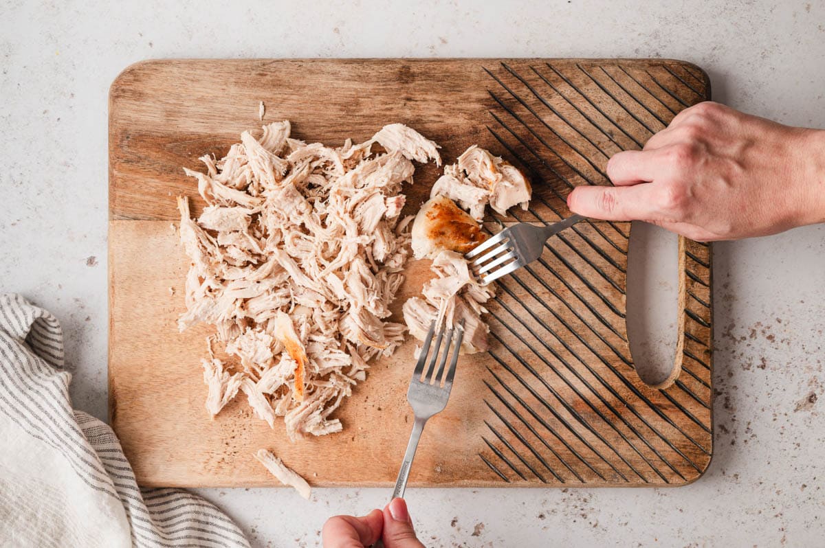 2 forks and shredded chicken on a cutting board.