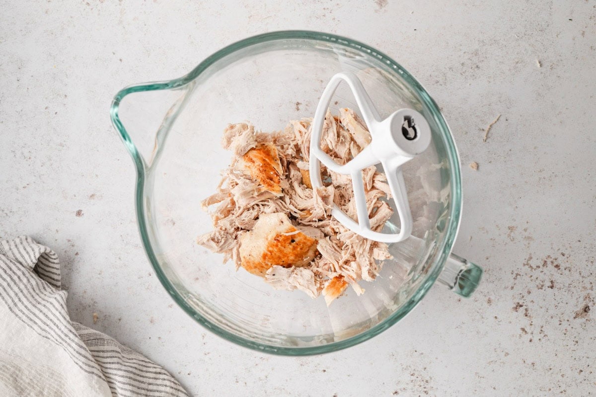 Stand mixer with a bowl of shredded chicken.