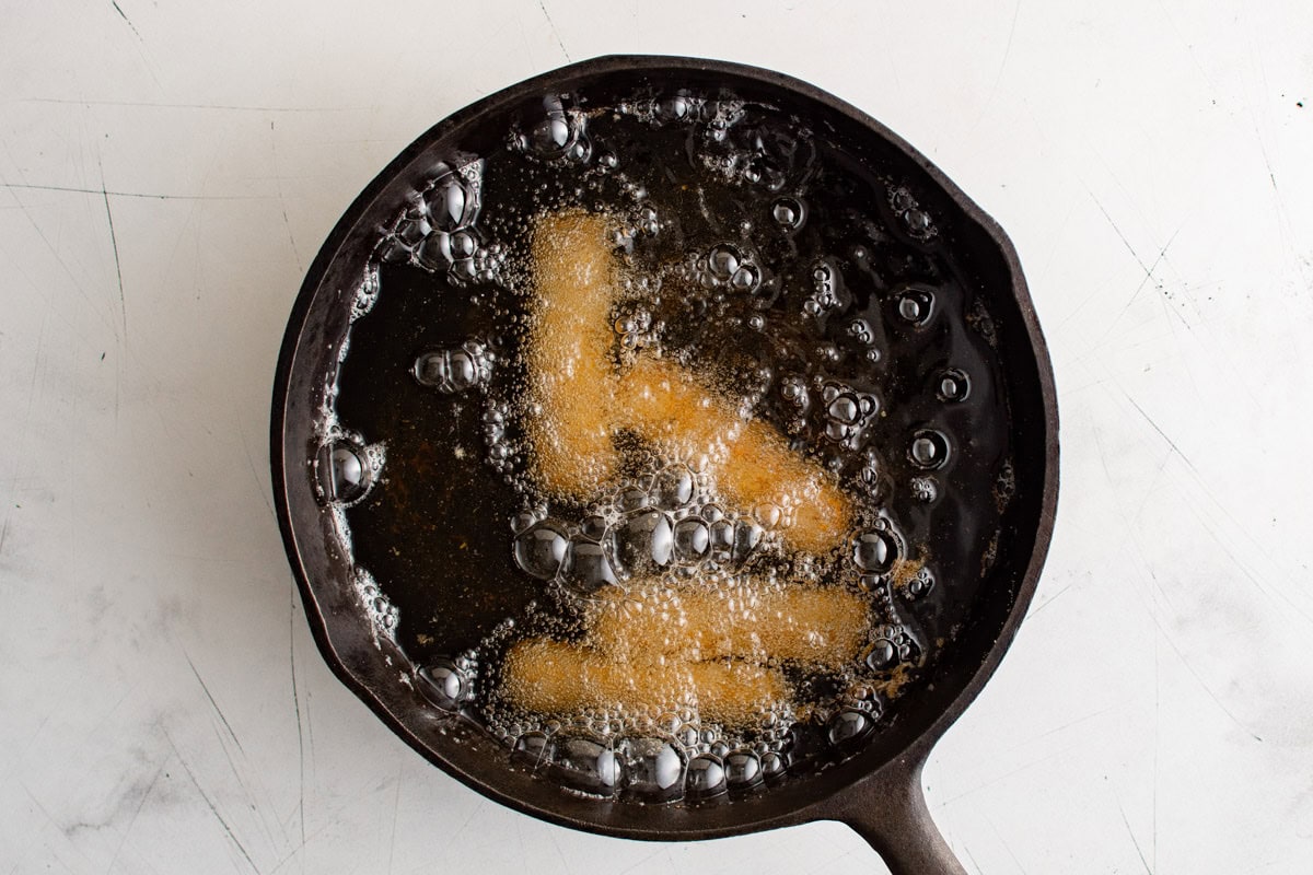 Mozzarella sticks frying in oil.