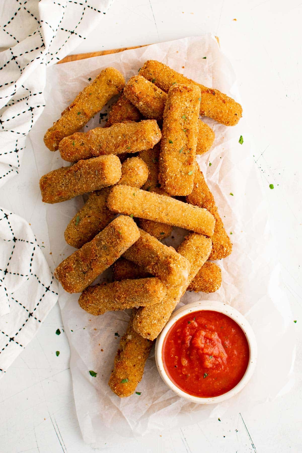 Stacks of mozzarella sticks and a dish of marinara sauce.