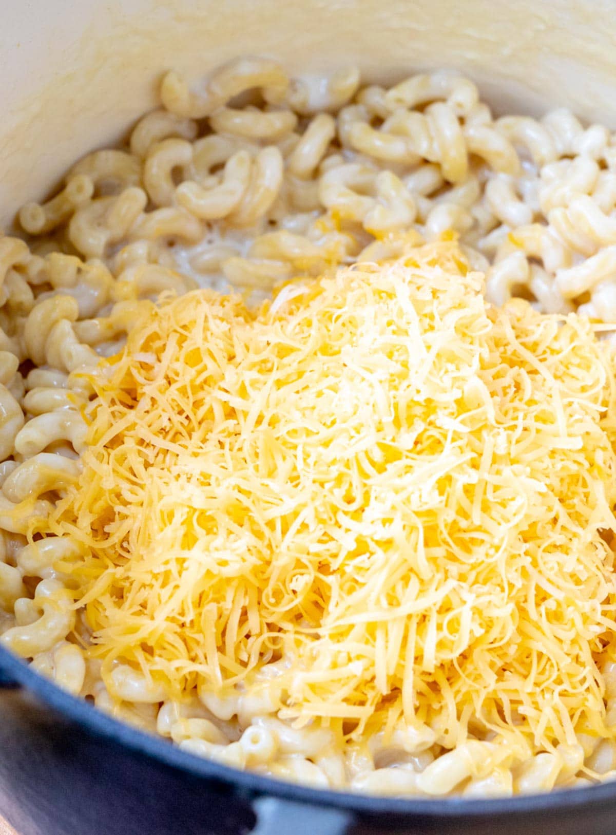 Shredded cheeses over cooked macaroni.