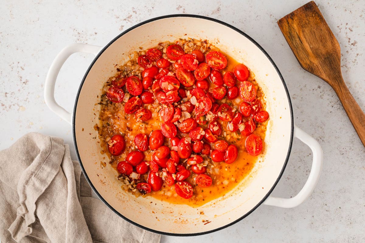 Sliced grape tomatoes in a sauce in a large skillet.