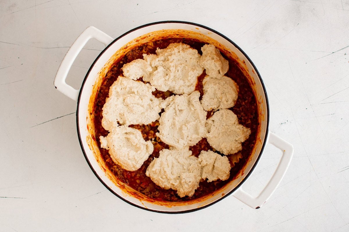 Ricotta cheese plopped on top of lasagna in a large pot.