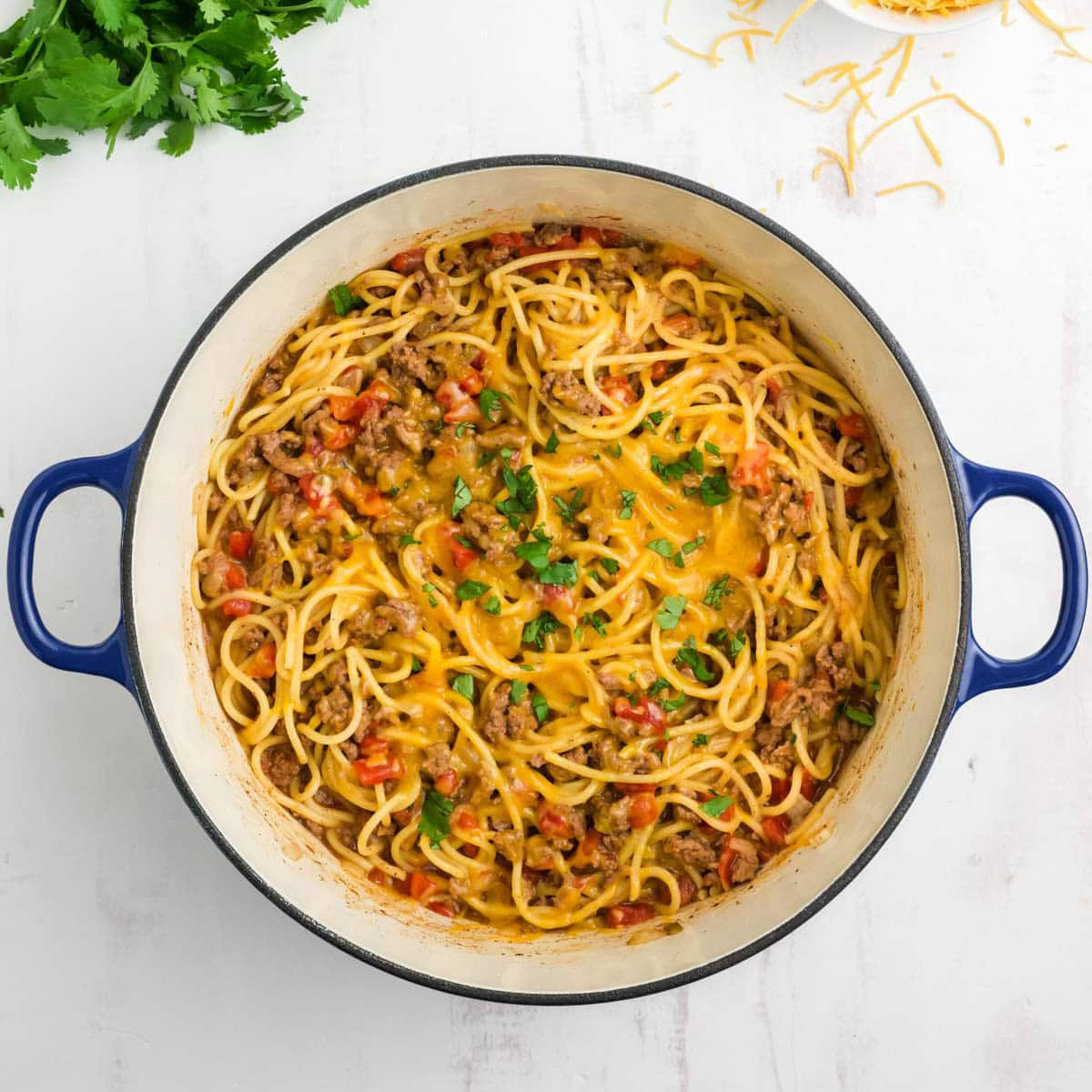 Taco spaghetti with melted cheese on top in a pot.