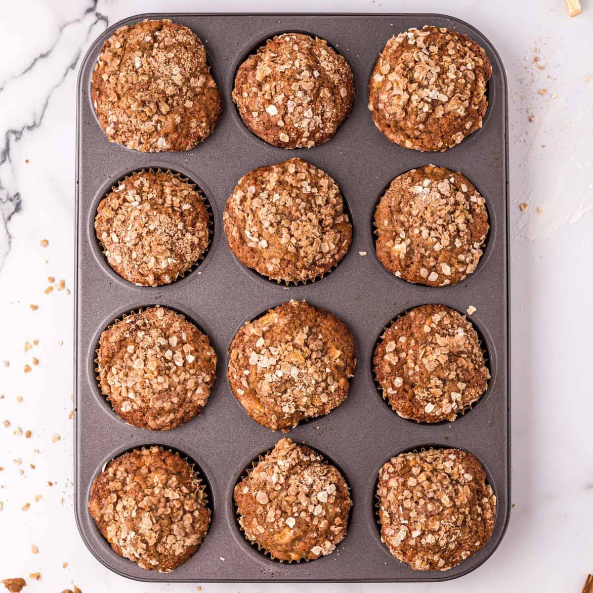 Baked apple cinnamon muffins in a muffin pan.