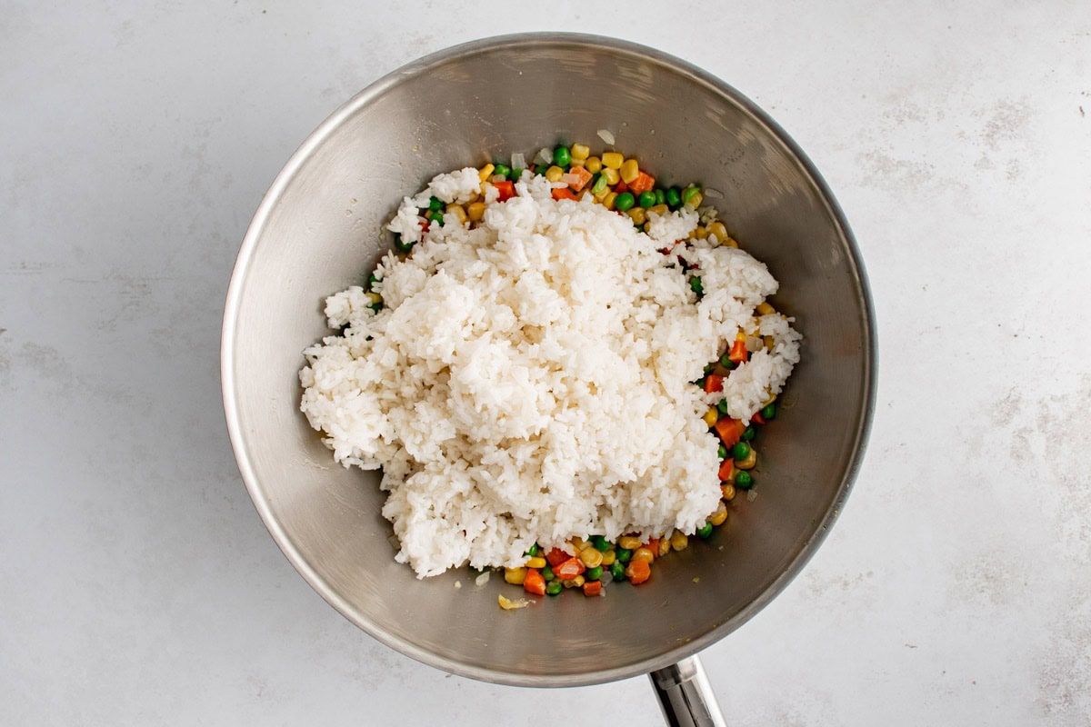 white rice in a skillet over vegetables.