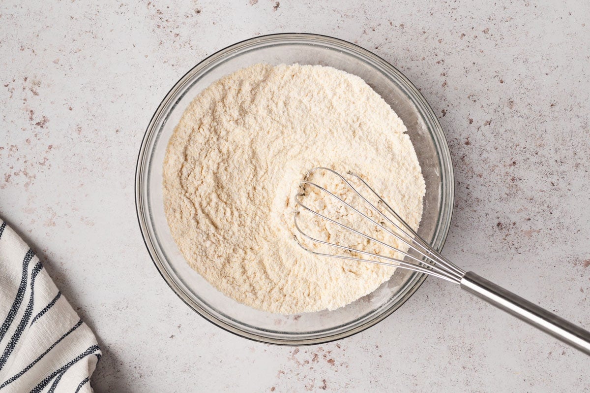 Flour mixture in a glass bowl with a whisk.