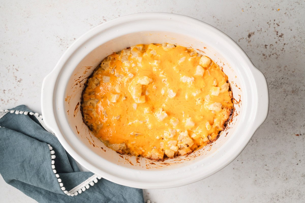 cooked cheesy potatoes in a white crockpot