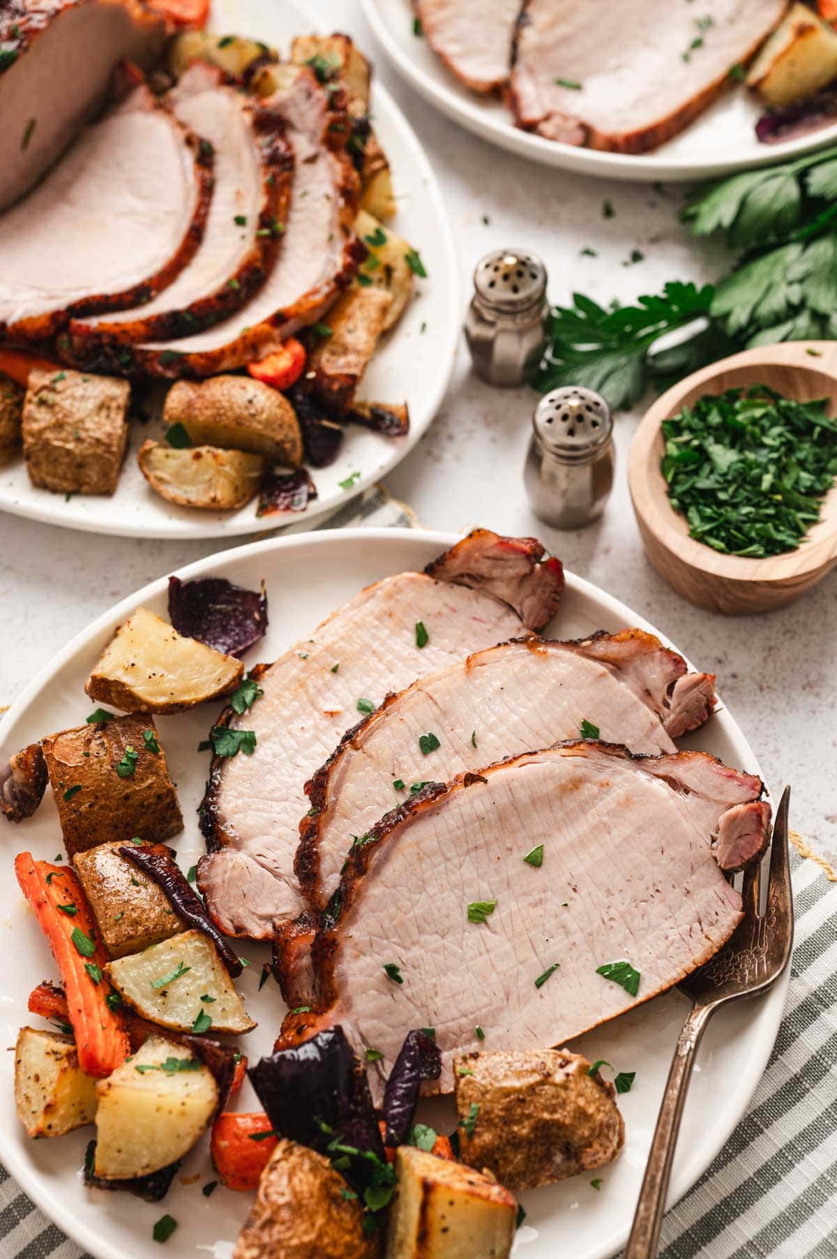 Sliced pork loan on a dinner plate with roasted veggies.