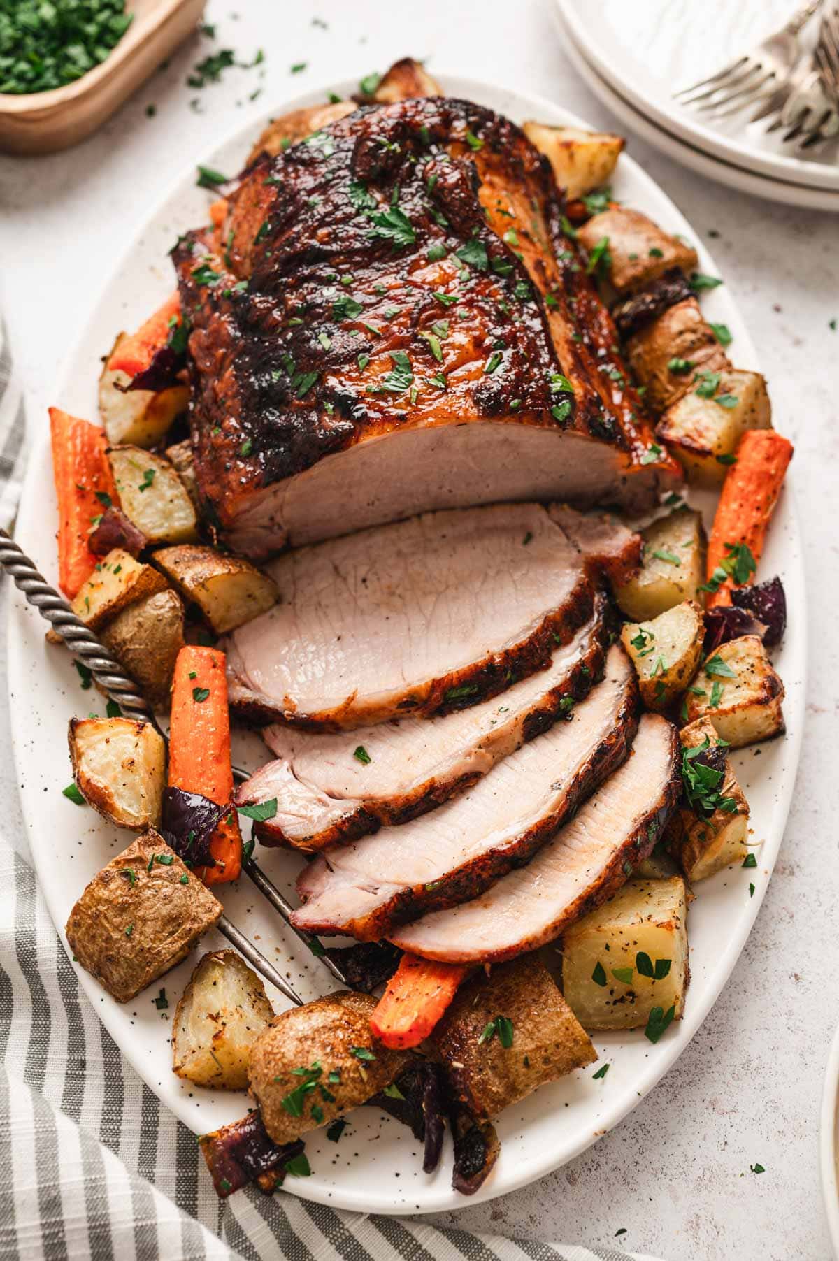 Roasted pork loin on a white platter with roasted veggies