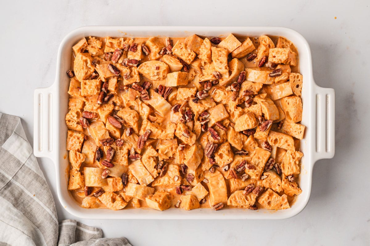 Unbaked pumpkin bread pudding in a white baking dish