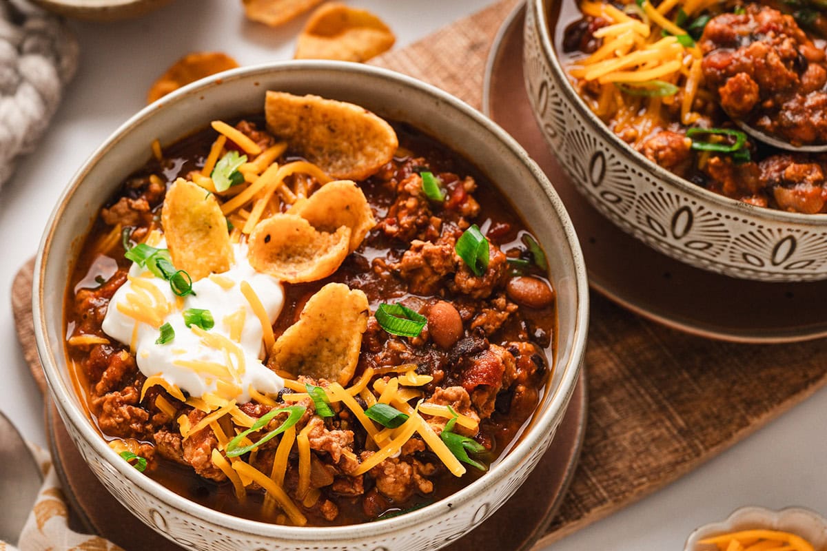 bowl of chili with fritos, sour cream, cheese and onions.