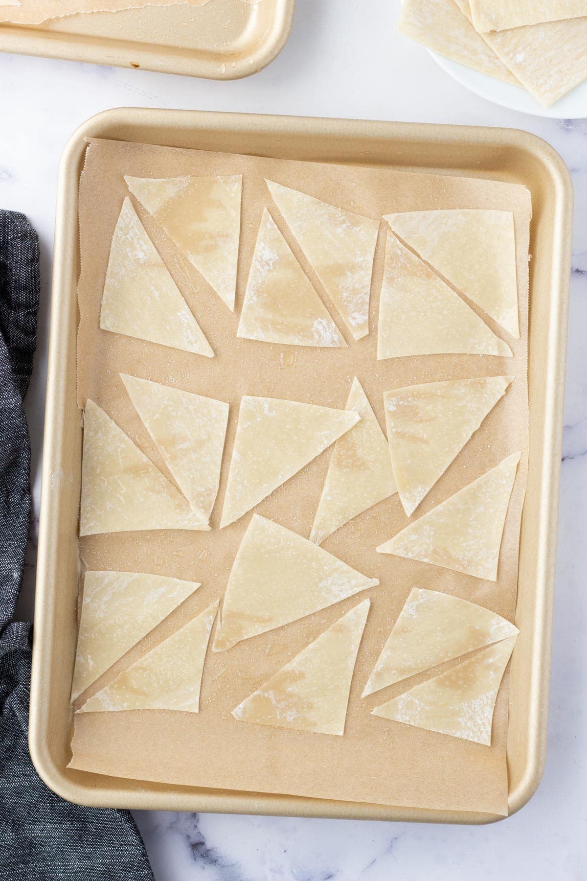 Uncooked Wonton wrappers on a baking sheet.