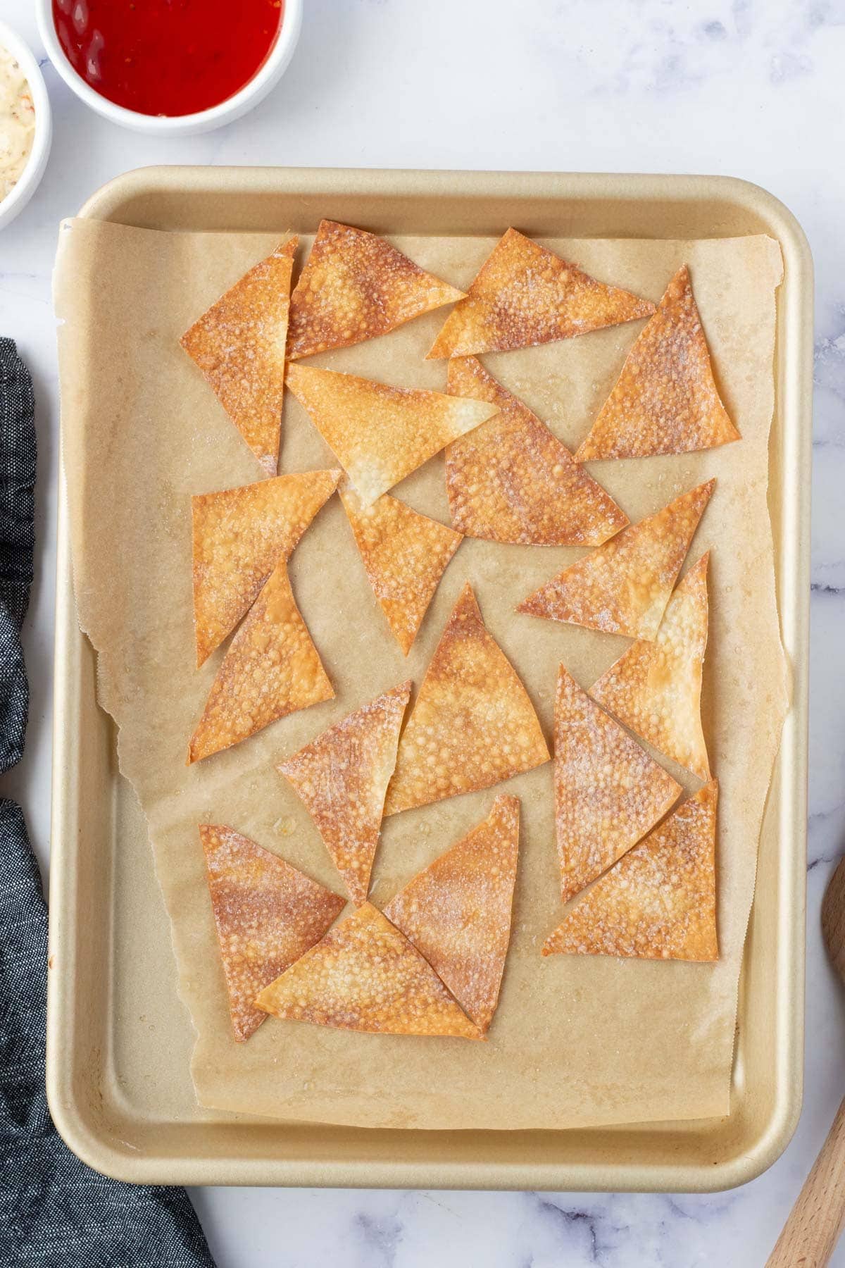 Cooked Wonton chips on a baking sheet.