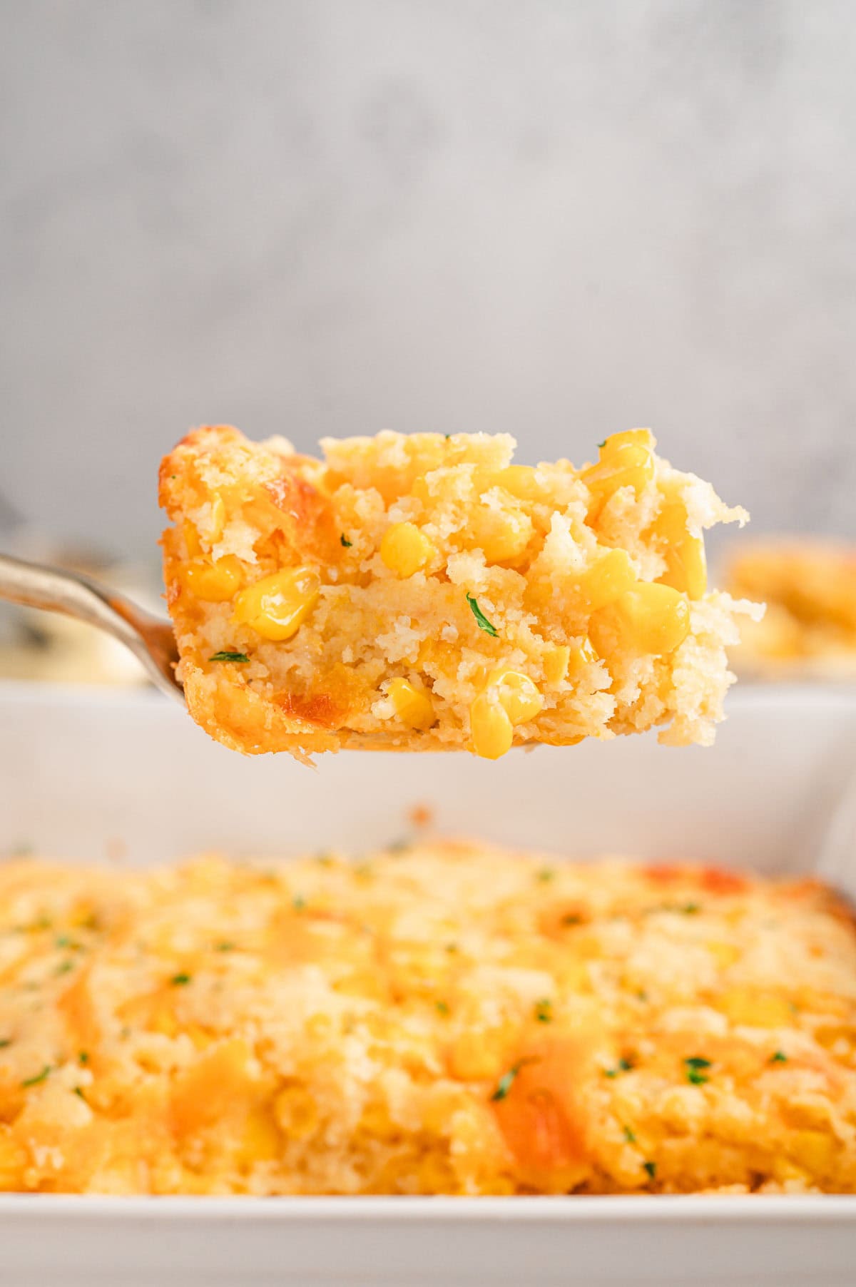 Slice of cornbread casserole held up by a spatula.