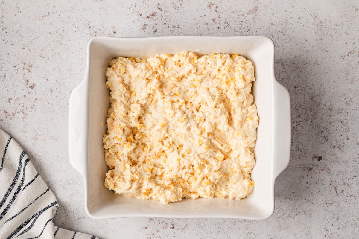 Cornbread casserole batter in a white baking dish. 