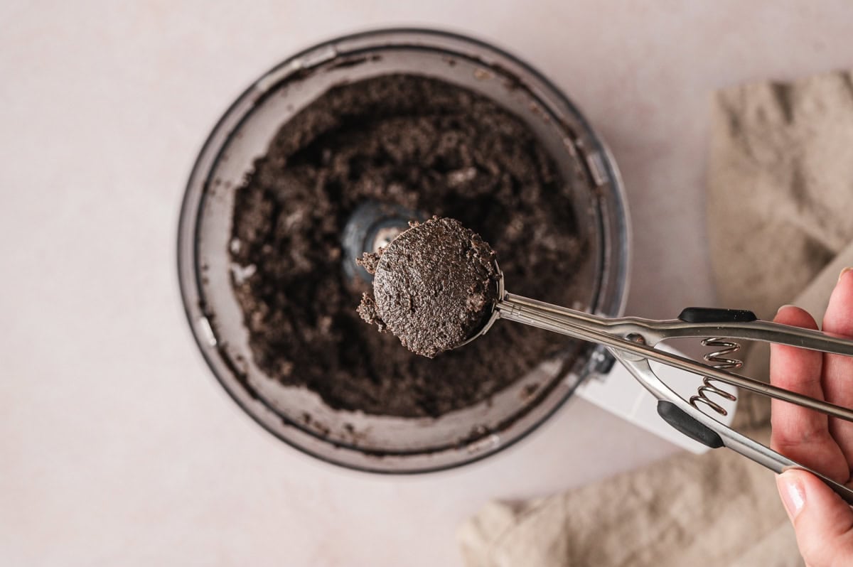 Crushed Oreos and cream cheese mixture with a cookie scoop.