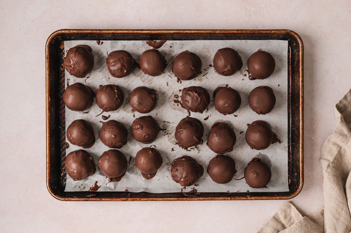 Chocolate covered Oreo truffles on a baking sheet.