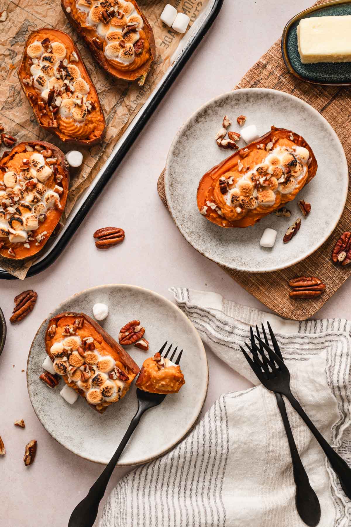 Twice baked sweet potatoes on small white plates with forks.