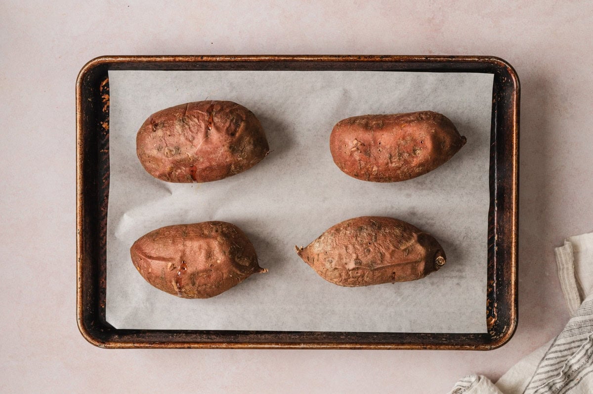 Roasted sweet potatoes on a sheet pan.