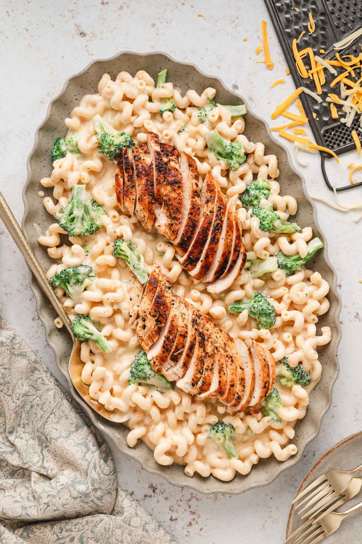 Mac and cheese on a large platter topped with sliced chicken.