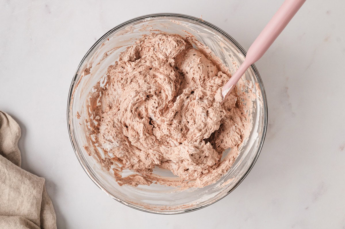 chocolate whipped cream in a glass bowl with a wooden spoon