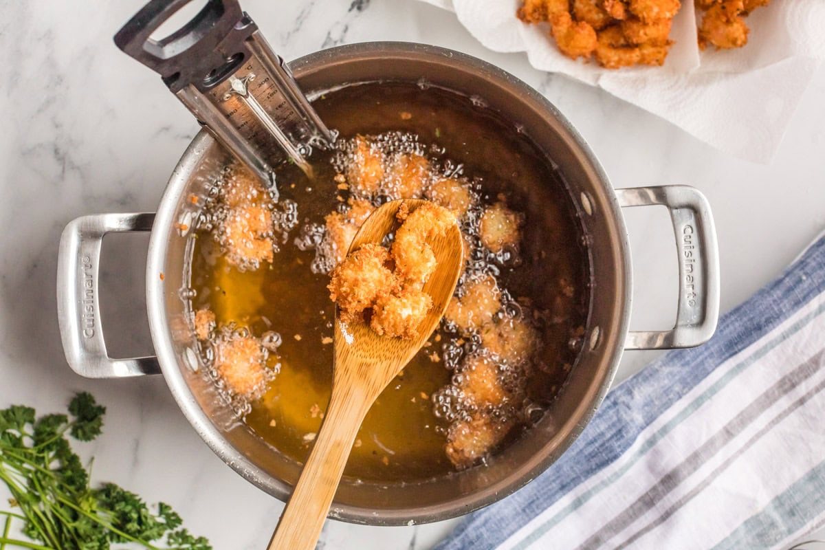 a wooden spoon holding some fried shrimp