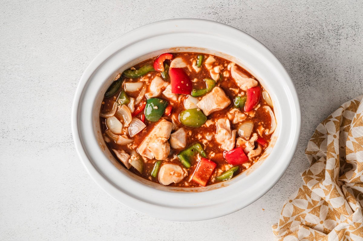 Chicken and veggies in a sauce in a slow cooker.