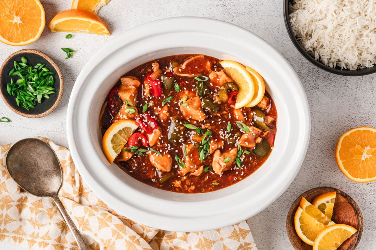 Cooked orange chicken and vegetables in a slow cooker.